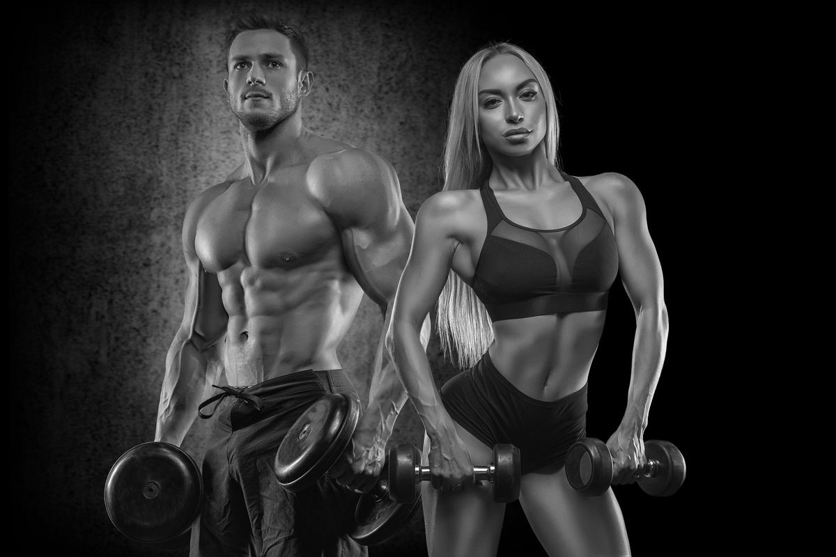 A sportive young couple posing in front of a camera on a dark background, playing sports, wearing beautiful sportswear, sharing sports, bodybuilding, fitness. Training of the biceps.